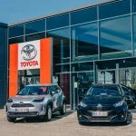 To Toyota biler, der holder ude foran en Toyota forhandler