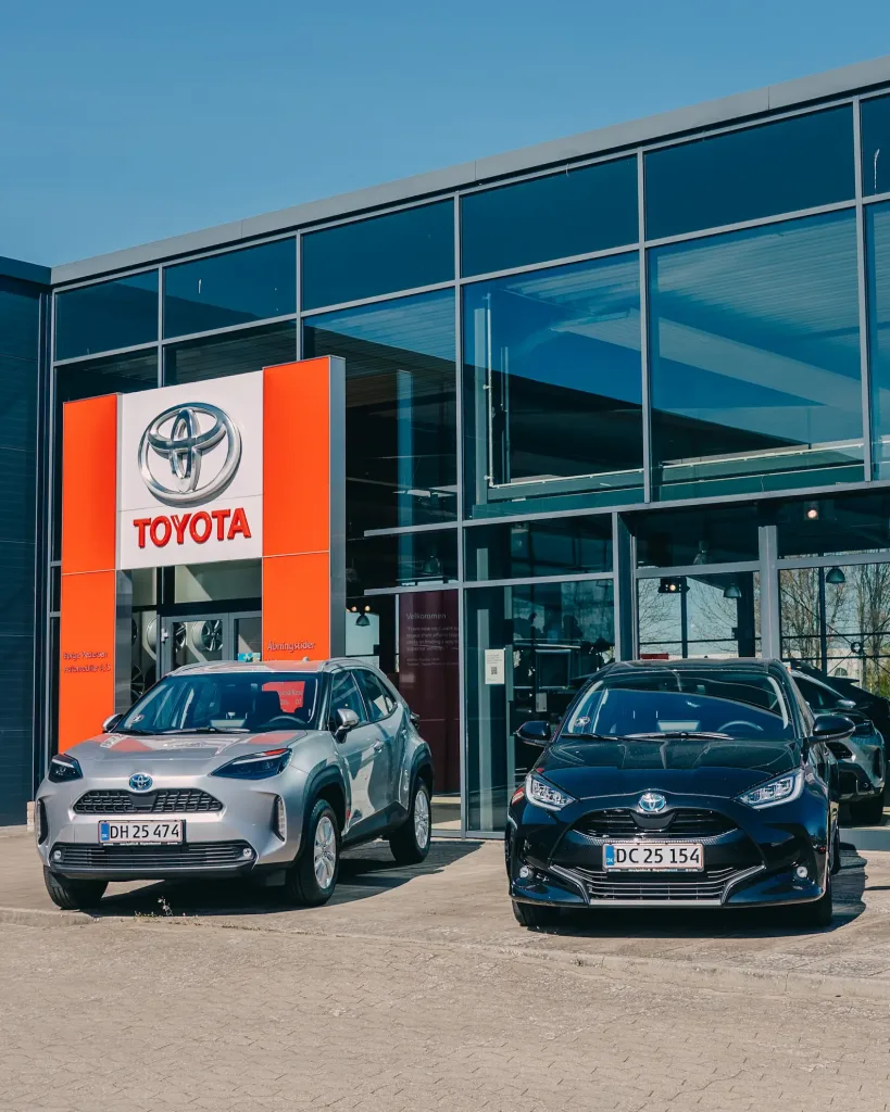 To Toyota biler, der holder ude foran en Toyota forhandler