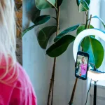 En telefon i et ringlight, hvor kvinden filmer sig selv