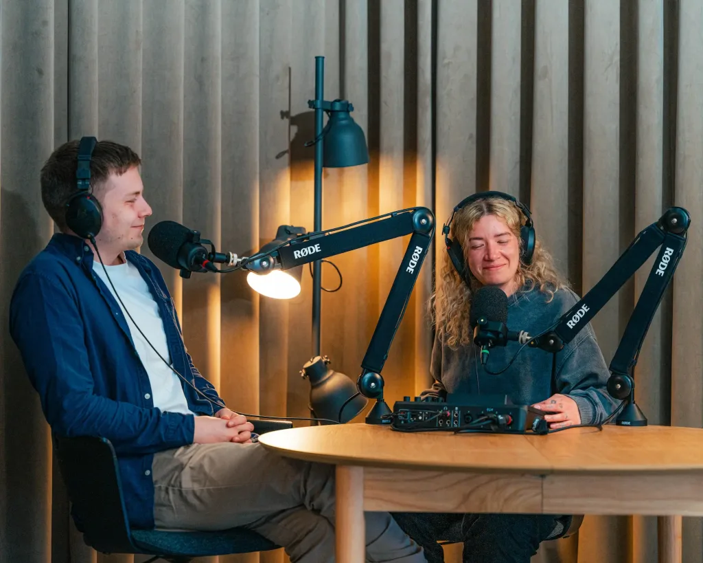 To mennesker der sidder sammen i et podcaststudie og har det sjovt